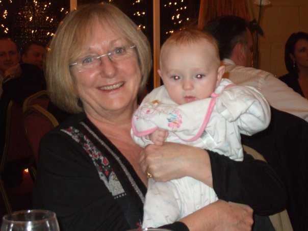 Sylvia Barry, smiling, holding a baby.